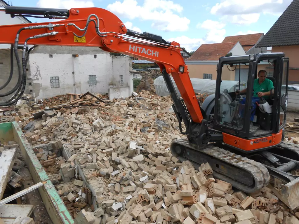 Bauarbeiter in einem roten Bagger bei Abbrucharbeiten auf einer Baustelle