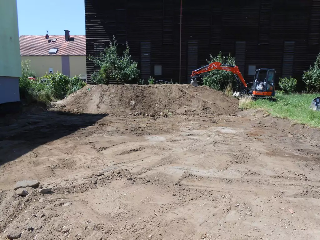 kleiner roter bagger schaufelt Erde auf einen Erdhügel