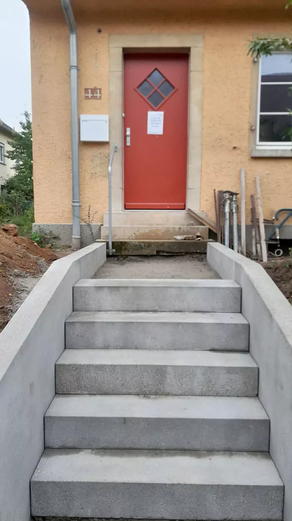 Steintreppe führt zu einer roten Eingangstür