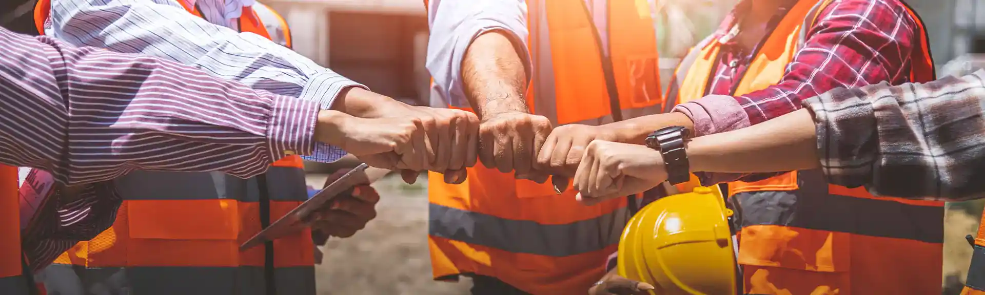 5 Handwerker, die die Hände zusammentun um den Teamzusammenhalt zu symbolisieren